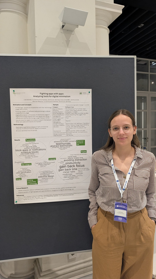 The image shows a vertical indoor shot of a young woman standing to the right of a scientific poster mounted on a dark blue display board. The woman has shoulder-length brown hair and wears round glasses. She is smiling kindly directly at the camera. She is dressed in a vertically striped button-down shirt in brown and white, paired with loose-fitting light brown trousers. Her hands are casually placed in her pockets. Around her neck, she wears a white and blue lanyard with the text "ICSOB 2024" and an attached conference badge.