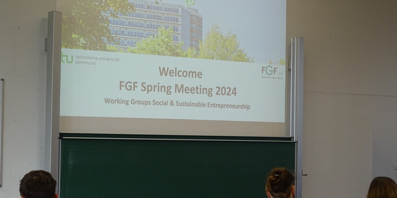 FGF Working Groups A picture of the welcome presentation at the Spring Meeting. You can see the first slide projected onto the wall and people sitting in front of it from behind.