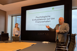 Zwei Personen halten einen Vortrag bei der degöb Jahrestagung 2025, im Vordergrund ist ein Konferenztisch zu sehen