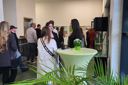 Graduates and guests stand together around the bar table.