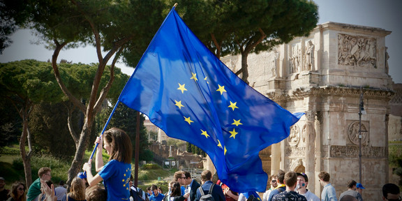 Young woman with flag of Europe in crowd.