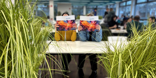 Zwei Studierende lesen die Mundo. Sie halten die Zeitschrift vor das Gesicht.