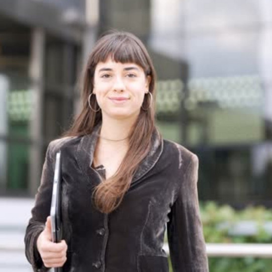 Woman with notebook in her arms in front of modern building with glass walls