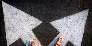 Someone stands with his feet at the beginning of two arrows pointing in different directions