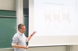 Vortragender vor Präsentation auf Leinwand. 