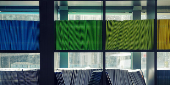 Foto: Regal mit vielen Fächern, jedes Fach voller Hefte in jeweils einer Farbe