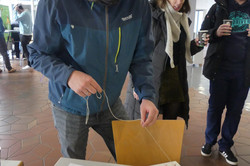 Mann überlegt, wie er Faden auf einem Brett mit mehreren aufgezeichneten Punkten und Nägeln am besten legen kann.
