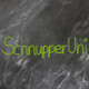 The text "SchnupperUni" written in green chalk on a not quite cleanly wiped blackboard, next to it a painted magnifying glass and a half-filled test tube