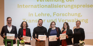 Foto von Preisträger*innen (v.l.): Prof. Matthias Faes, Prof. Angela Madeo, Dr. Maximilian Hartmann, Dr. Debra Hanning und Frigga Göckede gemeinsam mit der Prorektorin Internationales Prof. Tessa Flatten (r.).