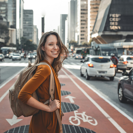 Woman on cycle path between two large roads, high-rise buildings on both sides