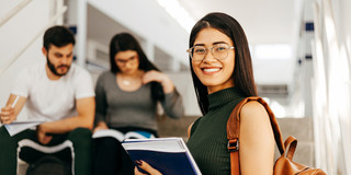 Young smiling woman with notes, two other people in the background.