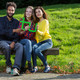 Three students sitting on a bench and holding a green TU logo in their hands together.