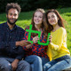 Three students sitting on a bench and holding a green TU logo in their hands together.
