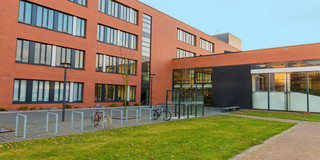 Building Seminarraumgebäude A large red building with green grass in front of it.