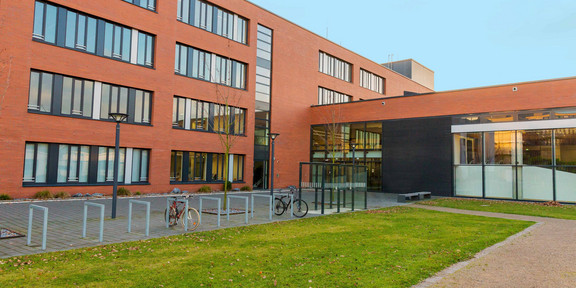Building Seminarraumgebäude A large red building with green grass in front of it.