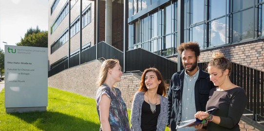 Vier Studierende stehen vor dem neu errichteten Physikgebäude.