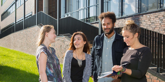 Four students stand in front of the newly constructed physics building.