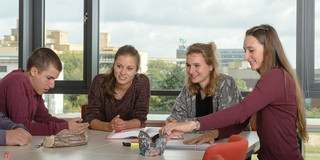 Students are sitting at a desk browsing in some documents.