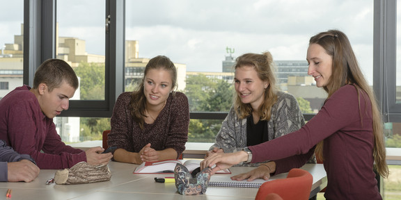 Students are sitting at a desk browsing in some documents.