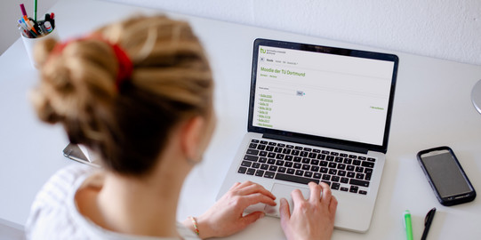 Foto einer Frau, die auf einen Laptop blickt.