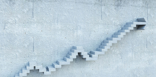 Career steps Stepped stairs protrude from a gray wall.