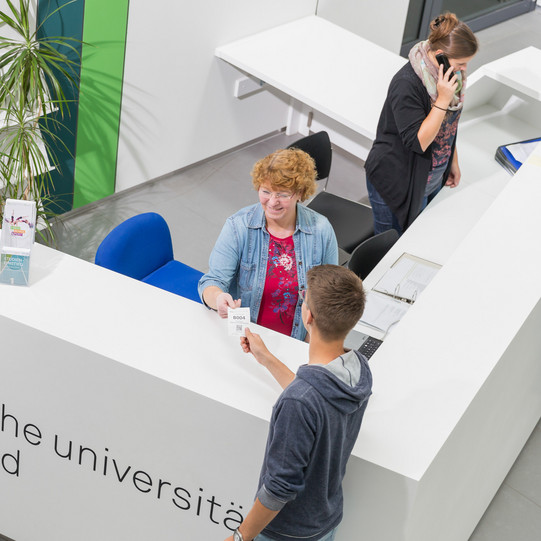 Studierendenberatung Ein Student gibt seine Wartenummer bei der Studienberatung ab.