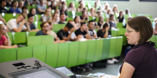 Lecturer sits in front of students in the lecture hall in the seminar building.