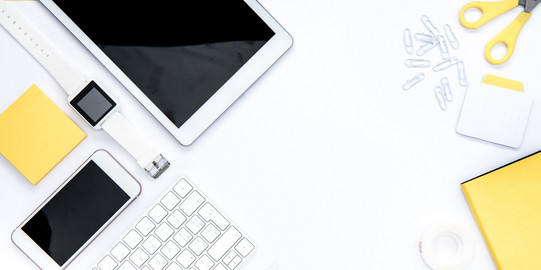 A tablet, a scissor, a smartphone, a notepad, a watch, a keyboard and a ruler are arranged on desk