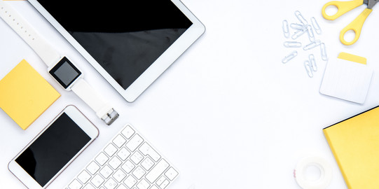 A tablet, a scissor, a smartphone, a notepad, a watch, a keyboard and a ruler are arranged on desk
