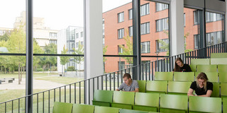 Students in lecture hall Three students are sitting in a lecture hall.