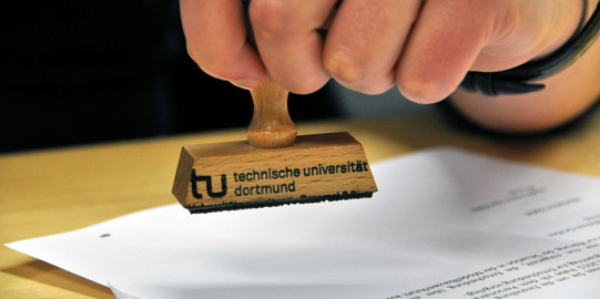 close-up of a hand holding a stamp over a piece of paper