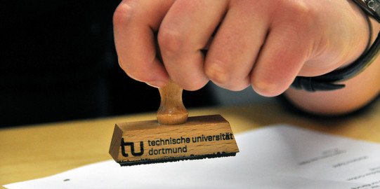 close-up of a hand holding a stamp over a piece of paper