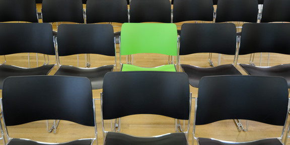 A green chair in the middle of black chairs