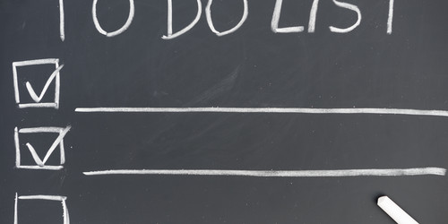  „TO DO LIST” is written on a chalkboard. underneath are lines and boxes. Two of the boxes are checked off