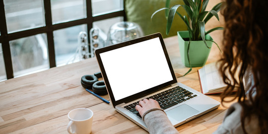 over-the-shoulder-Aufnahme einer Person, die am Laptop sitzt