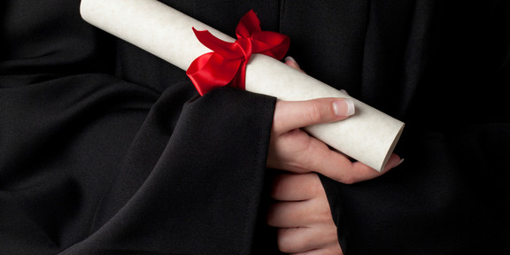 Urkunde Ein gerolltes Dokument mit roter Schleife wird von Händen gehalten.