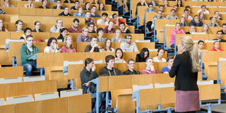 Studierende im Hörsaal Eine Dozierende steht vor Studierenden in der Vorlesung im Hörsaal.